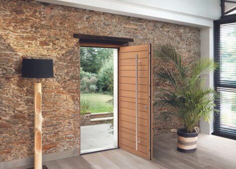 porte d'entrée en bois moderne avec une barre de tirage verticale dans une maison rénovée avec des murs en pierre