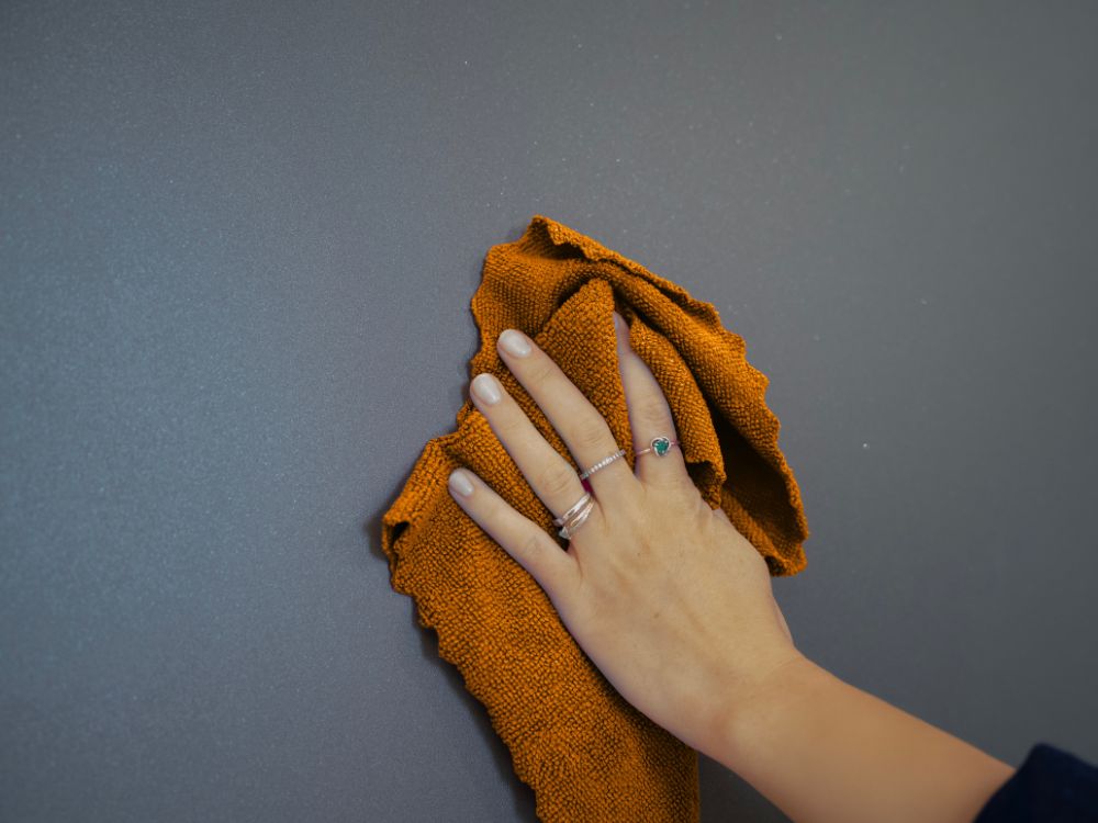 une main tenant un chiffon sur une porte d'entrée aluminium pour réaliser son entretien