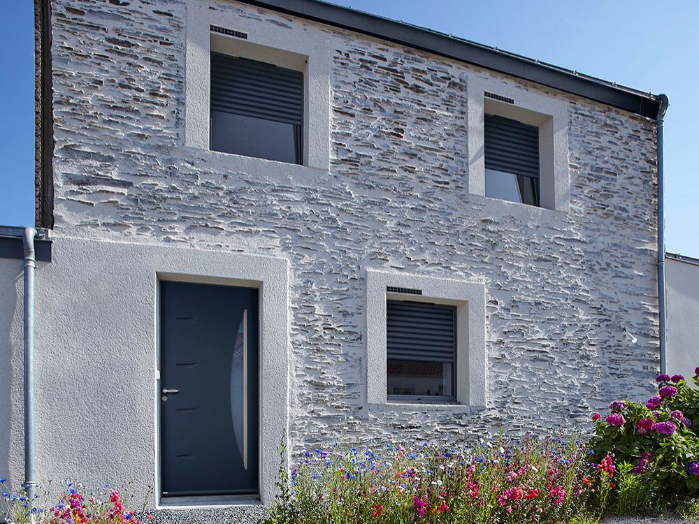 maison en pierre avec des fenetres équipées de volets roulants solaires