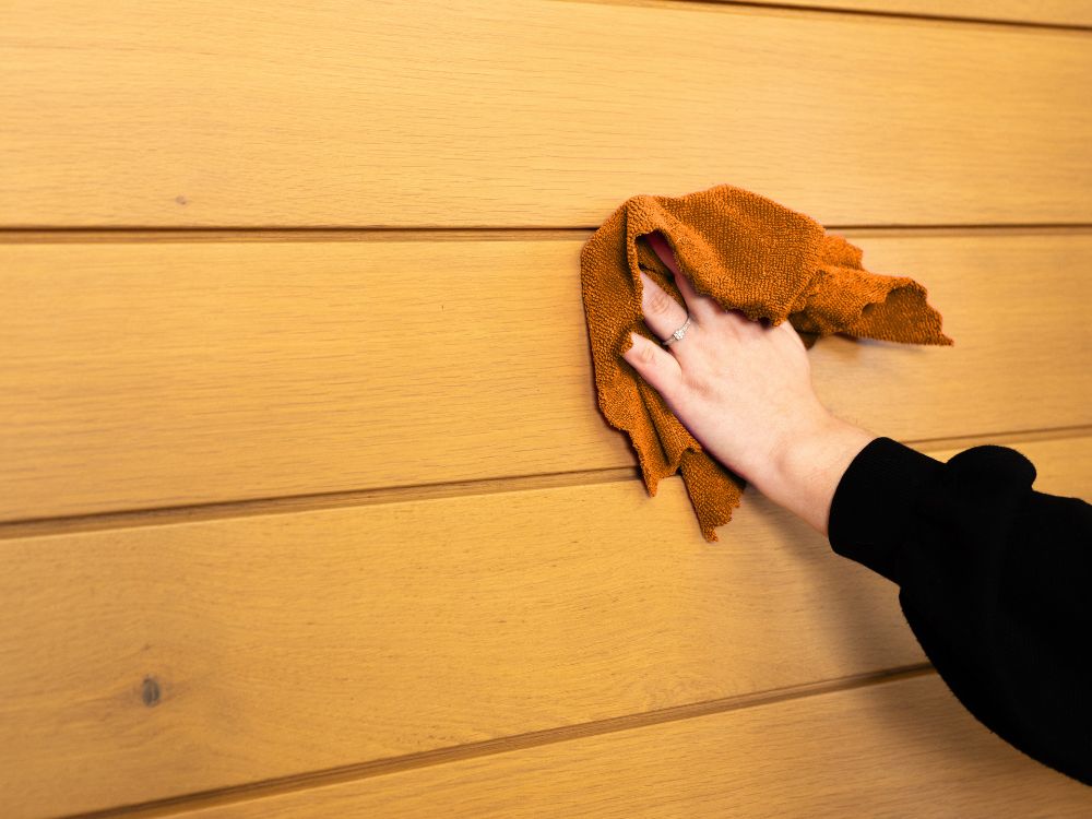 nettoyage d'une porte d'entrée en chêne avec un chiffon microfibre